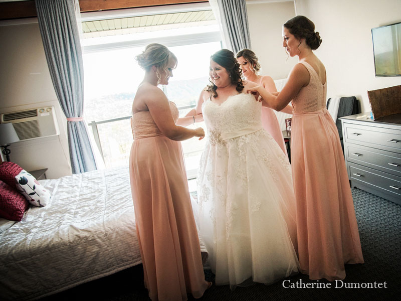 la mariée s'habille avec l'aide de ses filles d'honneur