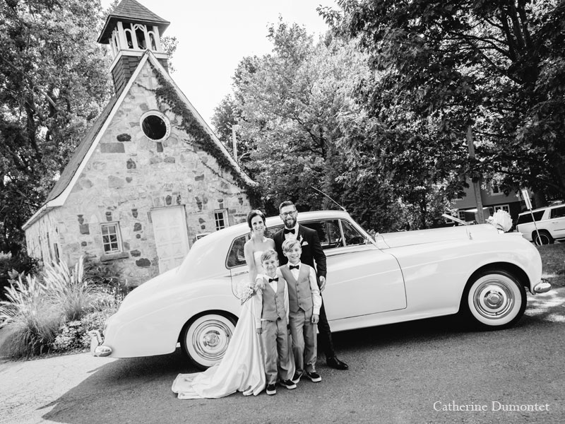 Les mariés à l'église devant la limousine