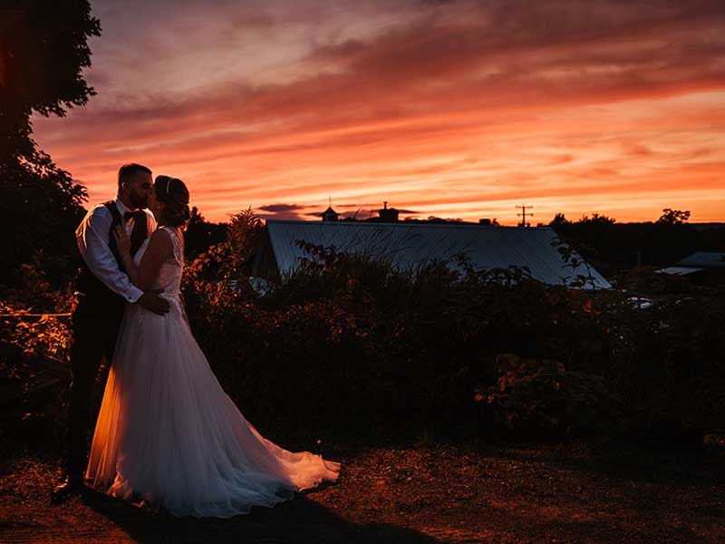 les mariés s'embrassent au coucher de soleil au Baluchon