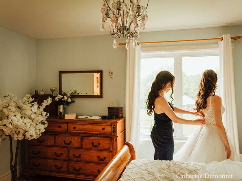 la mariée s'habillant avec l'aide de sa soeur