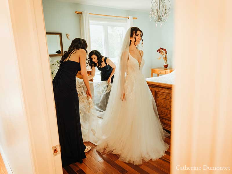 la mariée s'habillant avec l'aide de sa mère et sa soeur